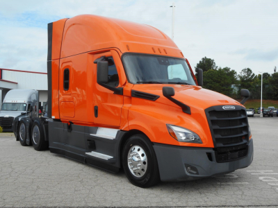 Freightliner Cascadia tractor head showing bright orange cab and black grille.