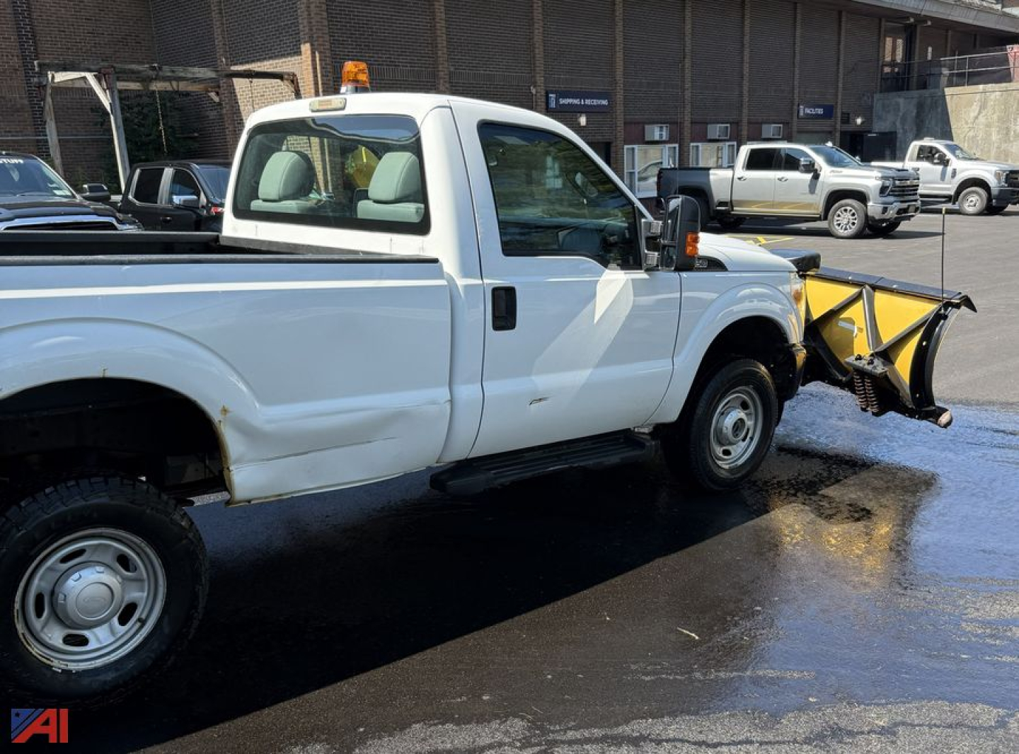 Ford F-250 Super Duty pickup with snow plow attachment in foreground, side view showing extended cab and plow blade, white paint, 4x4.