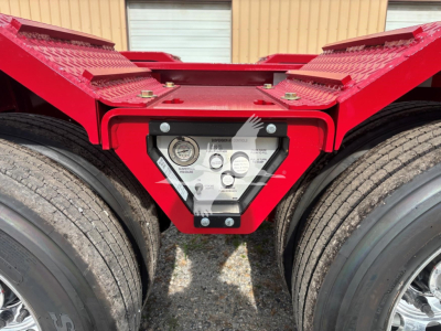 Trailer kingpin area showing gauge panel and red frame between dual rear axles of a Fontaine lowboy trailer.