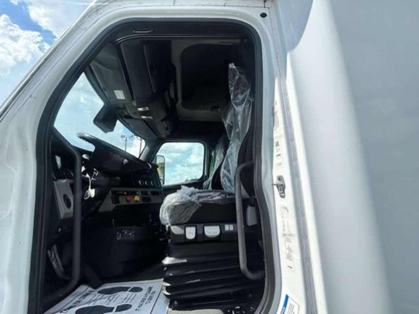 Truck cab interior of a 2022 Freightliner Cascadia 126 conventional sleeper showing driver seat and dashboard area