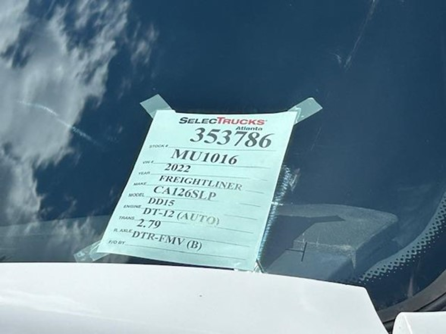 Tag on windshield showing stock number 353786, VIN MU1016, 2022 Freightliner Cascadia 126, DD15 engine, DT-12 auto, 2.79 axle ratio.