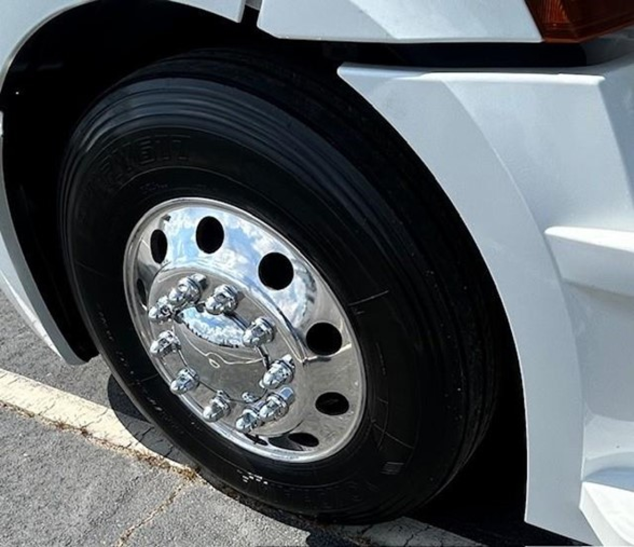 Truck wheel and rim close-up on a white Freightliner Cascadia 126 cab.