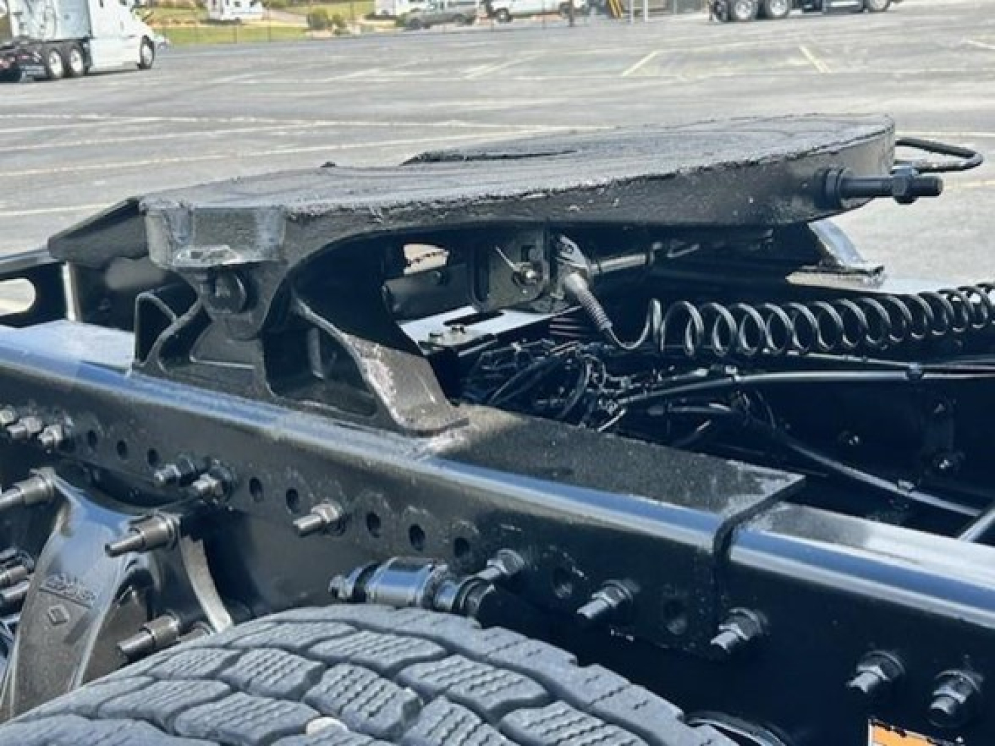 Freightliner Cascadia chassis showing springs, rails, and mounting hardware in a truck yard.