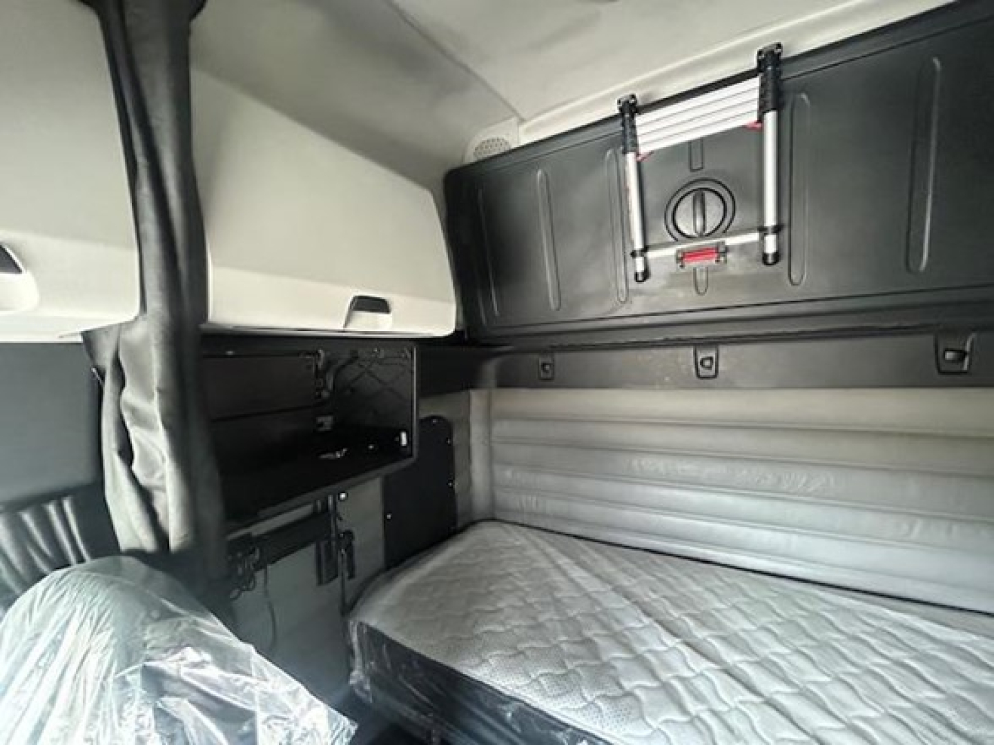 Freightliner Cascadia sleeper cab interior with storage cabinet and bunk bed area visible.