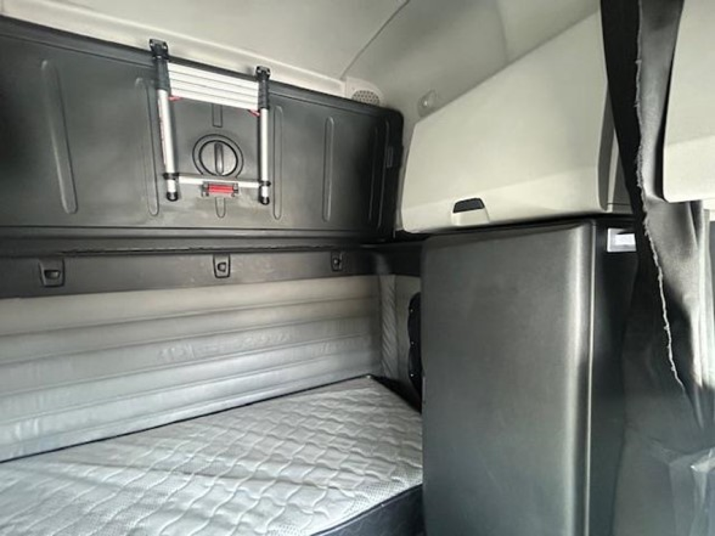 Freightliner Cascadia sleeper cab interior showing upper storage cabinet and bunk area.
