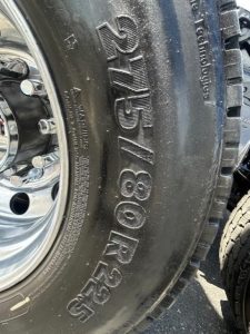 Truck wheel tire sidewall showing size markings 225/80R25 with chrome rim. Close-up view in daylight.