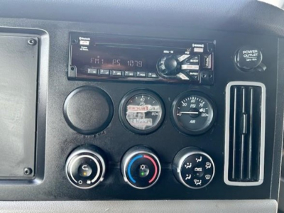 Dashboard of a Freightliner Cascadia 126 showing radio, gauges, and climate controls in a truck cab interior.