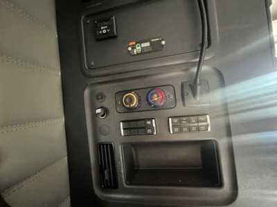 Dashboard controls of a Freightliner Cascadia 126 interior showing HVAC dials, switch panels, and storage pocket.