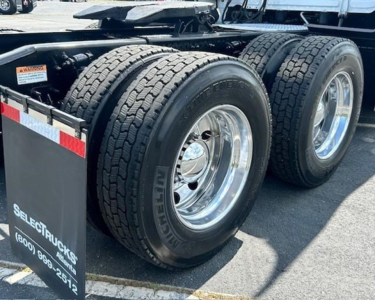Rear wheels and dual-tire assembly of a Freightliner Cascadia 126 truck showing large Michelin tires and chrome rims.