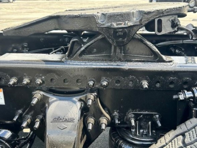 Freightliner Cascadia 126 trucking frame with fifth wheel hitch and engine components visible. Close-up of air suspension mounts and mounting bolts.