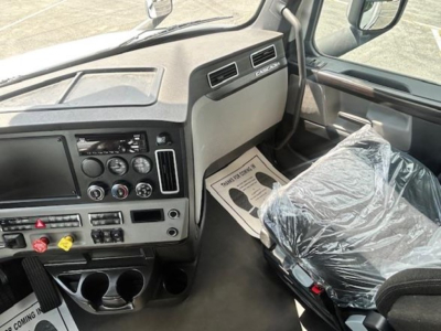 Freightliner Cascadia 126 truck interior cockpit view with steering wheel, dashboard controls, and driver seat wrapped in plastic.