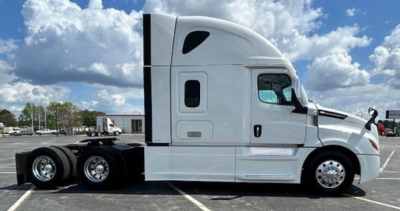 Semi truck side view showing a white Freightliner Cascadia 126 sleeper with twin rear axles and hooded cab, no visible text.
