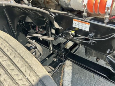 Cascadia truck chassis showing undercarriage components, hoses, and frame with warning sticker visible.
