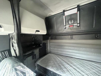 Freightliner Cascadia sleeper cab interior with storage cabinet and bunk bed area visible.