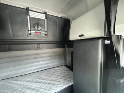 Freightliner Cascadia sleeper cab interior showing upper storage cabinet and bunk area.