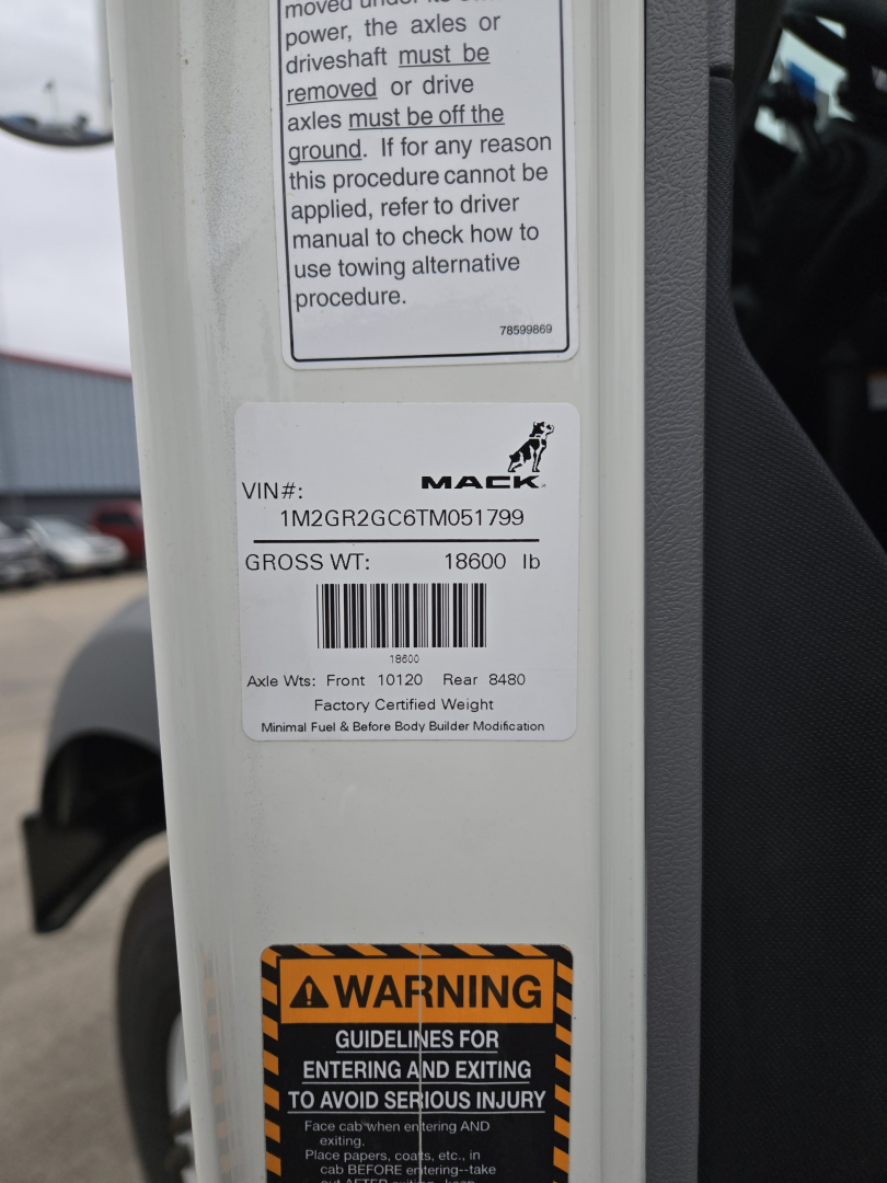 Mack GR64B VIN sticker label with VIN 1M2GR2GC6TM051799 and Gross Weight 18600 lb, safety warning label visible.