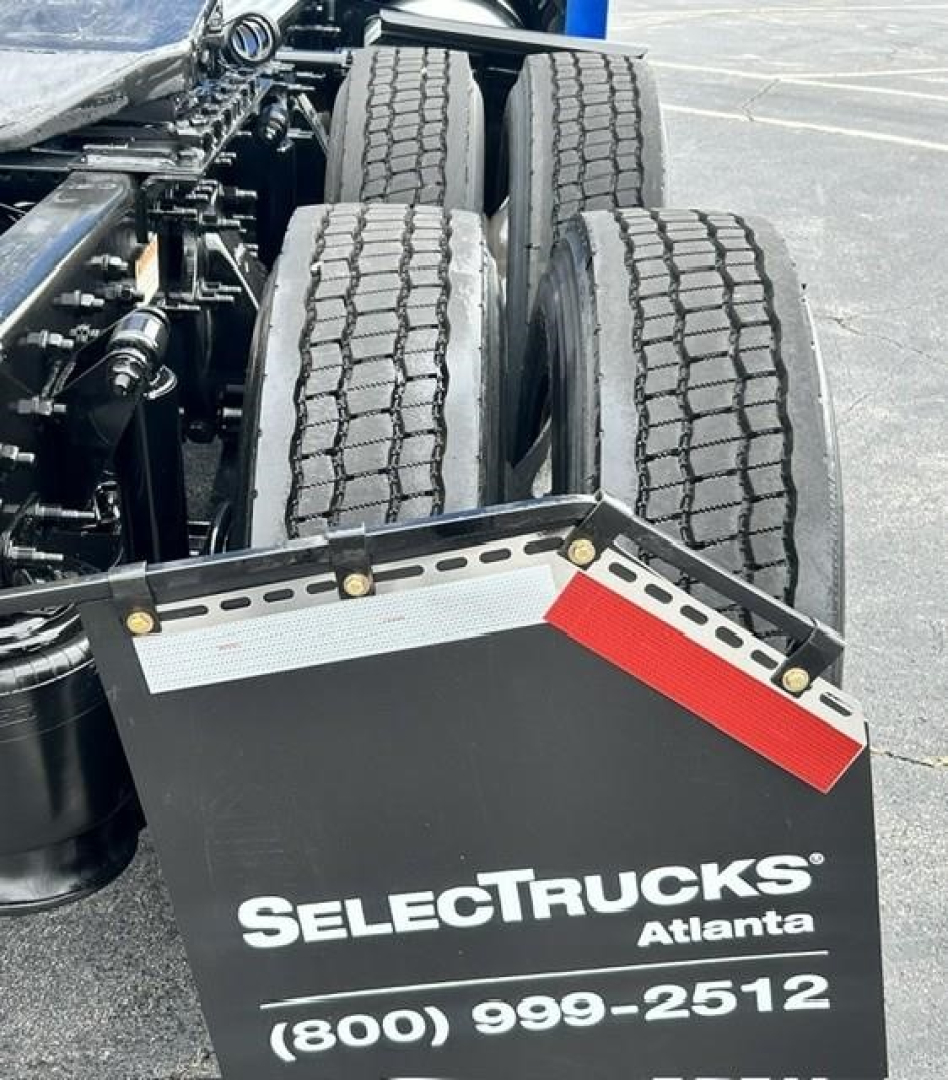 Rear view of a Freightliner Cascadia 126 truck showing dual rear axles and a mudflap with SelectTrucks Atlanta branding and contact number.
