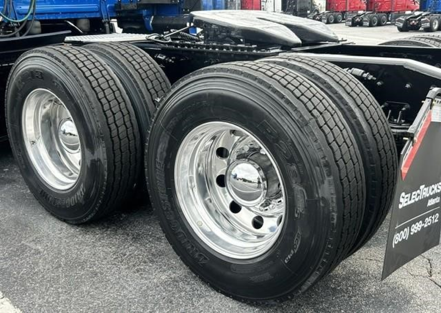 Freightliner Cascadia 126 tractor dual rear tires and chrome wheels on trailer; side view with fuel tanks and mudflap visible.