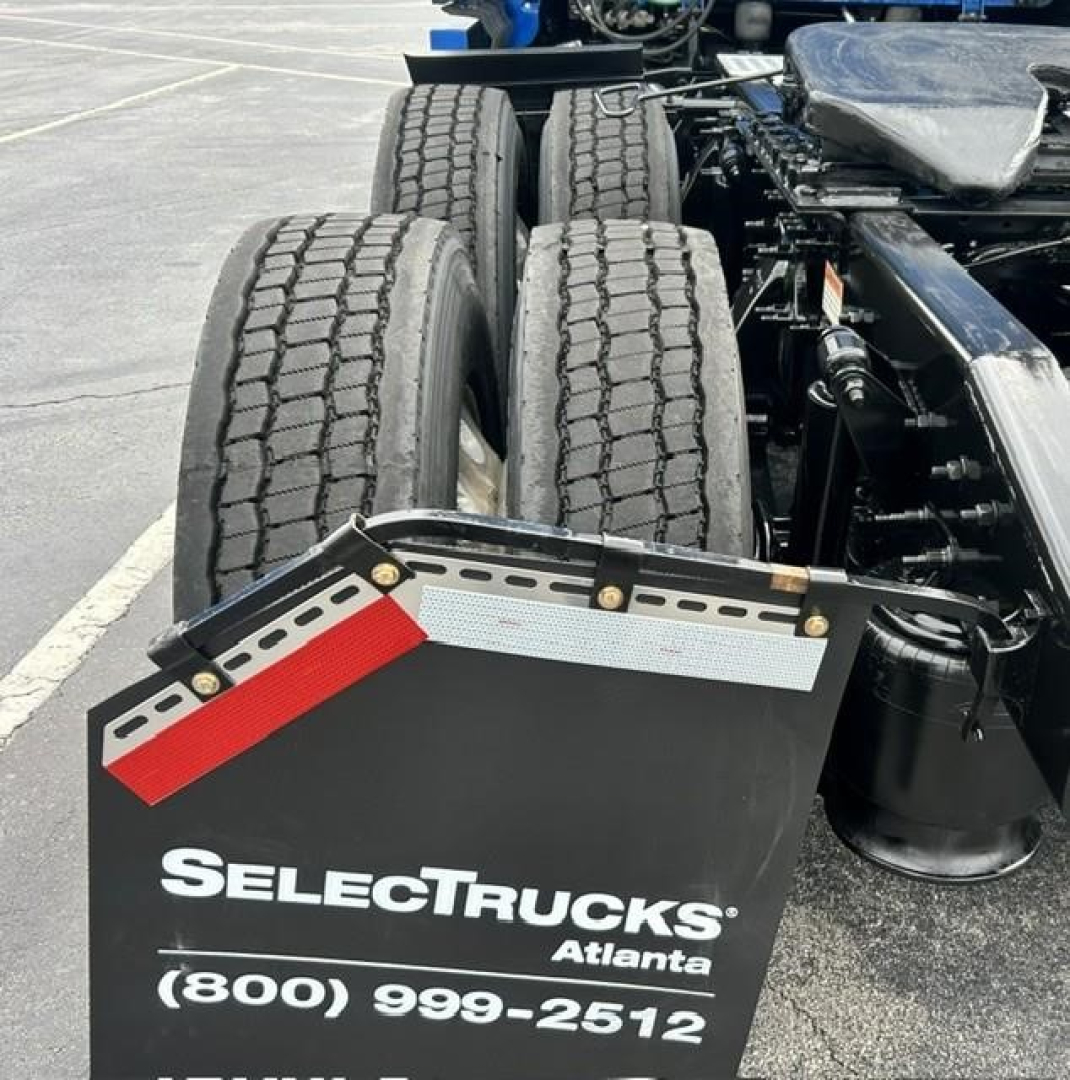 Rear view of a Freightliner Cascadia truck showing dual rear axles and mudflaps with a SelectTrucks Atlanta plate and contact number.