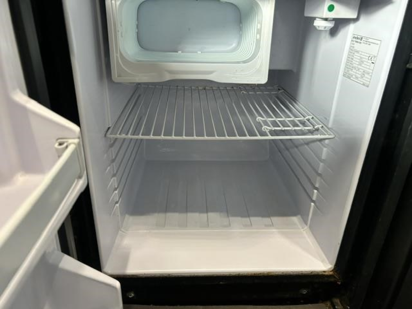 Refrigerator or freezer in a truck cab showing empty shelf and freezer door frame.