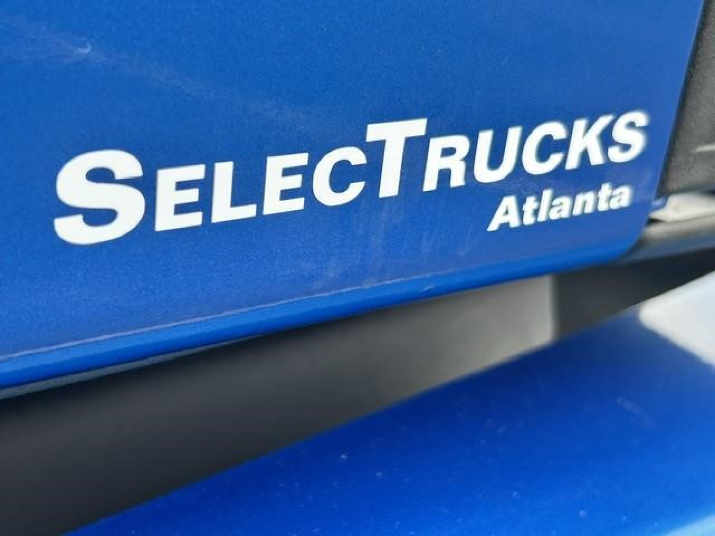 SelectTrucks Atlanta blue panel with white logo text 'SELECTTRUCKS Atlanta' on a Freightliner Cascadia truck,