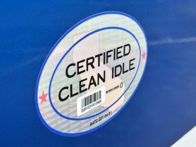 Truck tag sticker reading Certified Clean Idle on blue Freightliner Cascadia sleeper cab side.