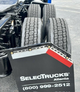 Rear view of a Freightliner Cascadia 126 truck showing dual rear axles and a mudflap with SelectTrucks Atlanta branding and contact number.