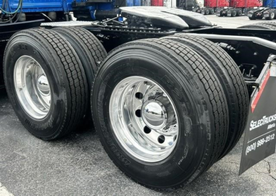 Freightliner Cascadia 126 tractor dual rear tires and chrome wheels on trailer; side view with fuel tanks and mudflap visible.