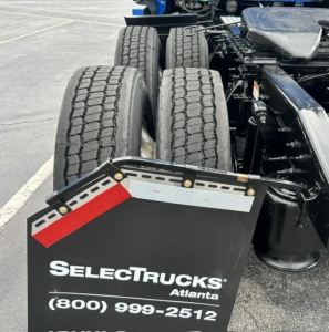 Rear view of a Freightliner Cascadia truck showing dual rear axles and mudflaps with a SelectTrucks Atlanta plate and contact number.