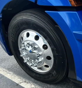 Truck front wheel and blue fender showing Bridgestone tire and polished chrome hub, with visible wheel and tire details.