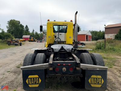Tractor trailer rear view showing yellow cab, dual rear tires, and NAPA mud flaps on a Freightliner FLD120 SD truck.