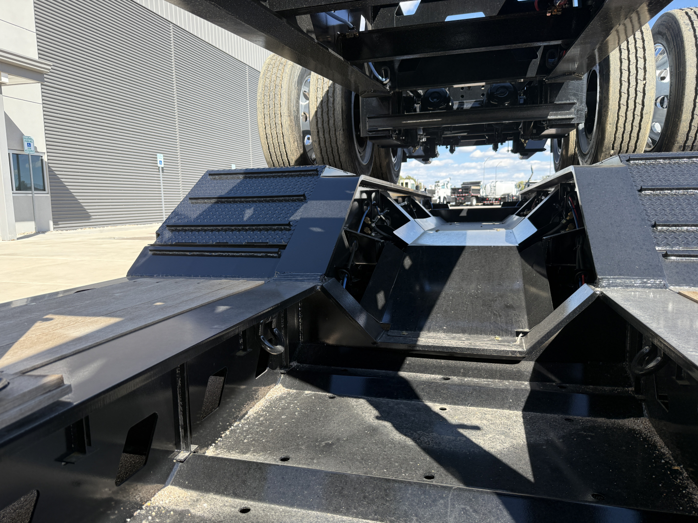 Alpha A120HDG-SF2 lowboy trailer undercarriage showing heavy-duty deck and rear axle area with wheel wells and black metal beams.