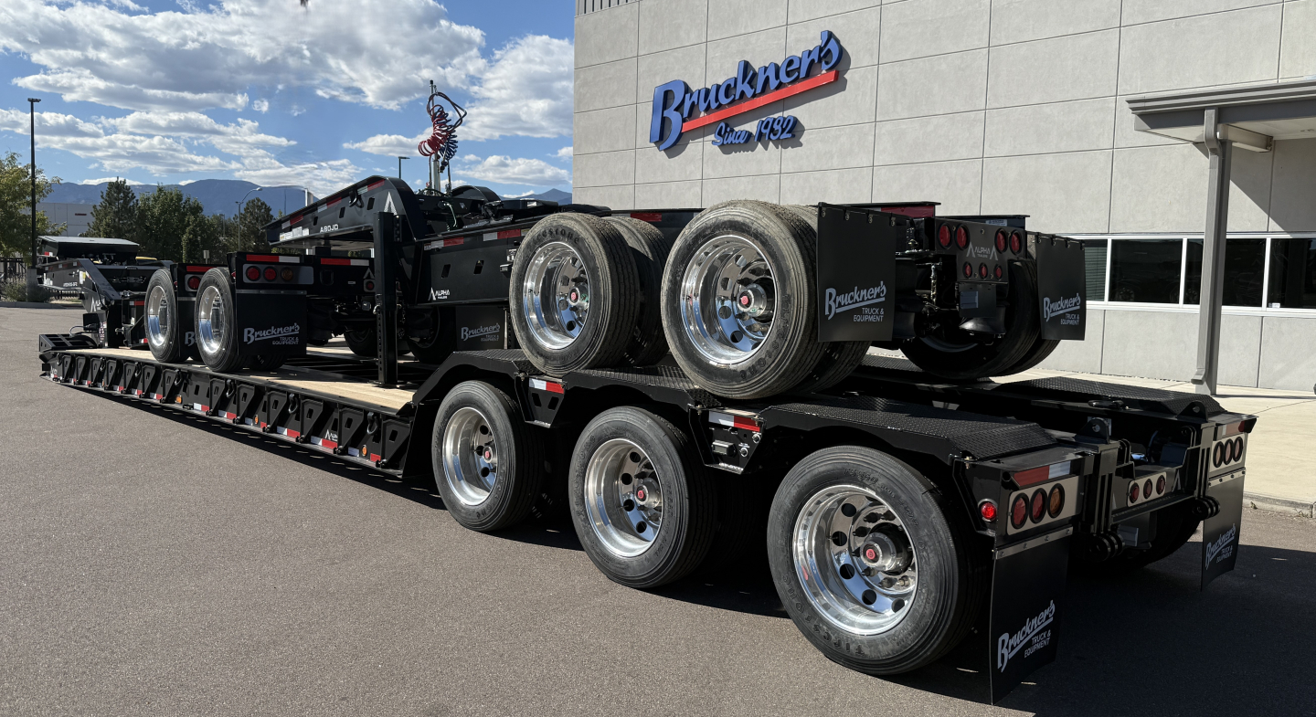 Trailer showing three-axle lowboy with dual rear axles and heavy-duty wheels, Alpha A120HDG-SF2 plate on deck.