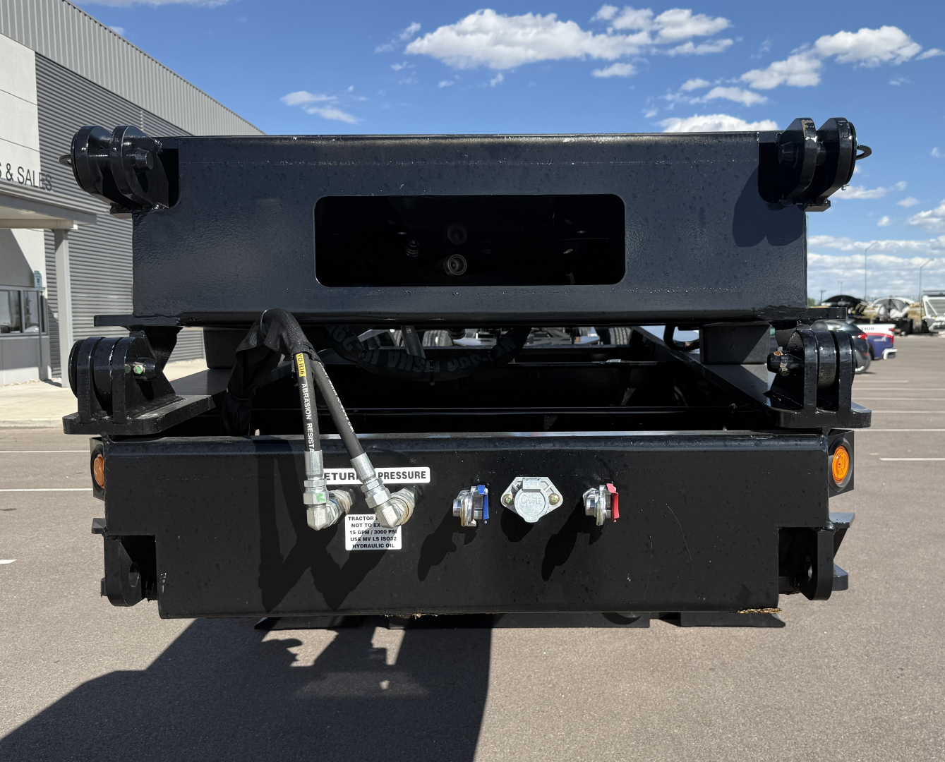 Trailer hitch assembly showing hydraulic manifold and control ports on a lowboy trailer front panel with labeled ports and fittings.
