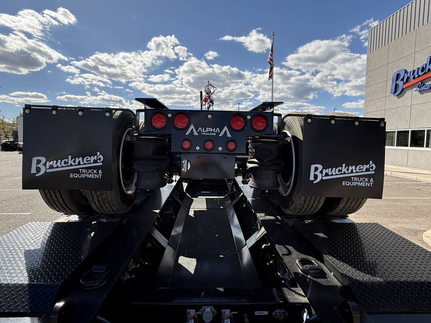 Alpha A120HDG-SF2 lowboy trailer rear view showing wheel fenders with Bruckners Truck & Equipment logos and rear frame with Alpha branding.