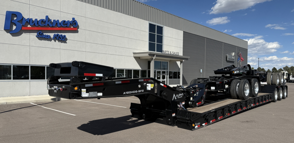 Alpha A120HDG-SF2 lowboy trailer in front of dealership building with brand logo Brückners Trucking.