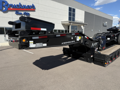 A black lowboy trailer with A120HDG-SF2 markings parked outside a dealership building.