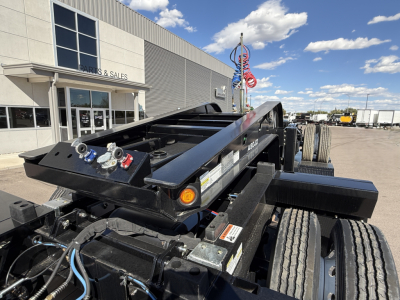 Alpha A120HDG-SF2 lowboy trailer showing hydraulic gooseneck and control valves, with hoses and dual rear tires visible.