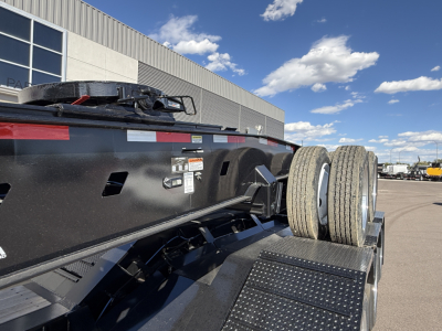 Trailer side view showing dual rear tires and black steel frame with reflective tape and service decals.