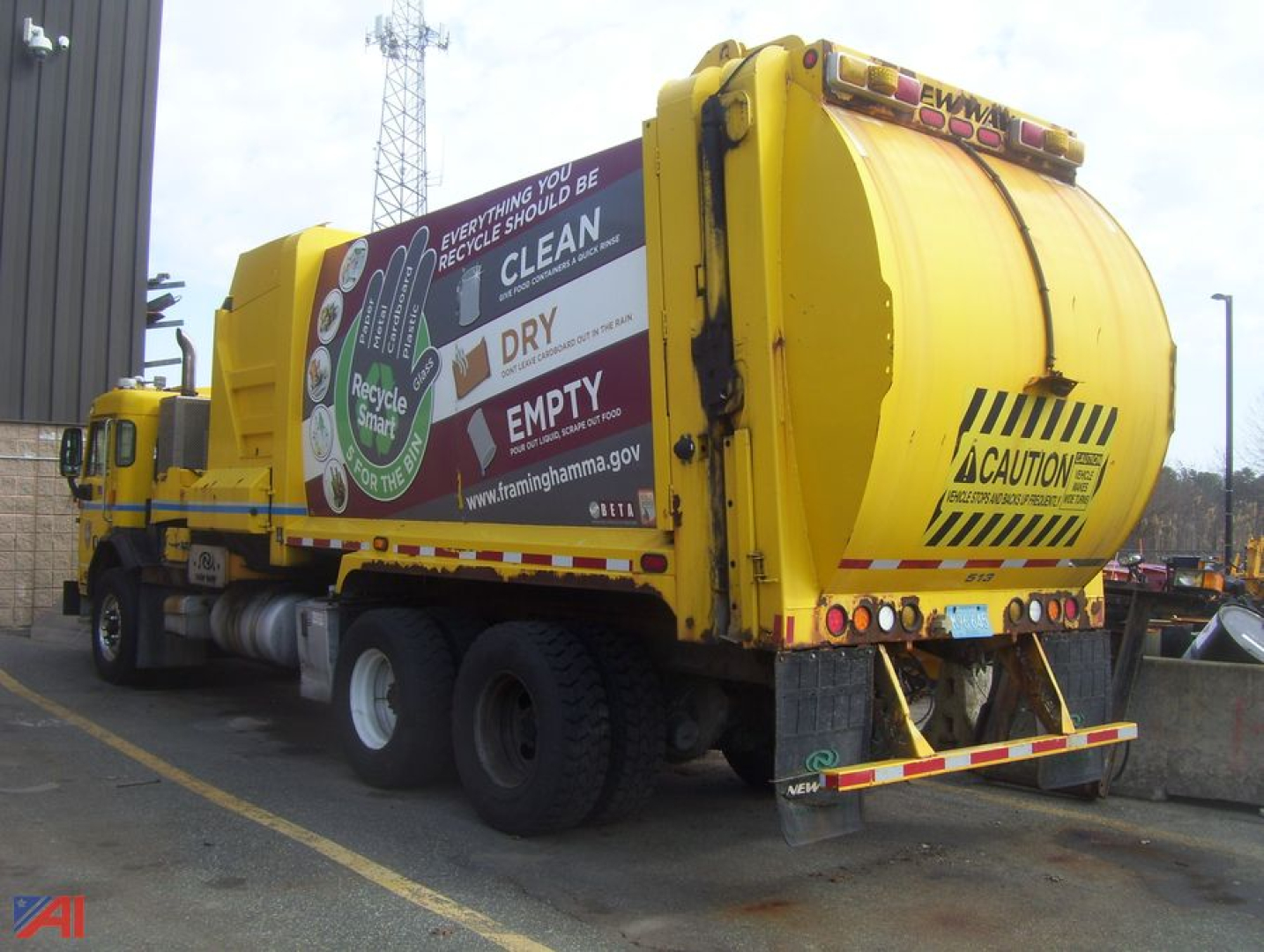 Peterbilt PB320 refuse side loader truck in yellow with rear compactor, side advertising on hopper, rear caution markings.