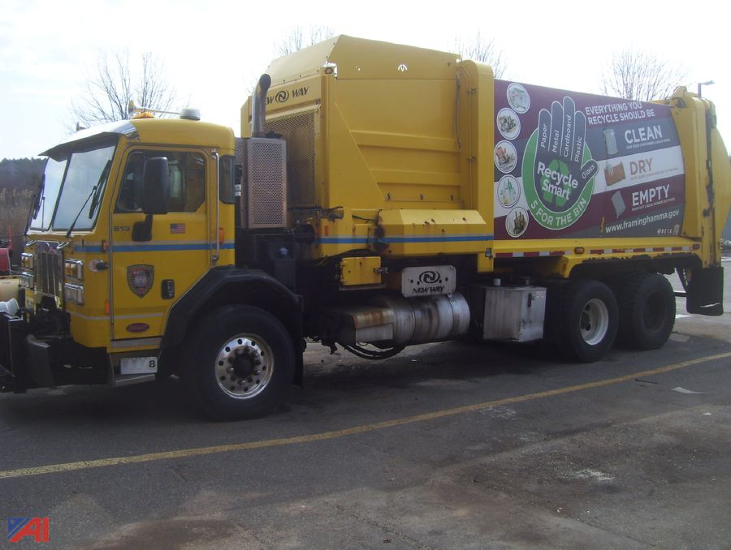 Peterbilt PB320 side loader refuse truck with a large yellow compactor body and recycling graphics on the side, cab at front, diesel exhaust stack visible.