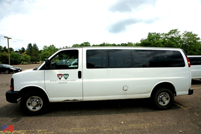 Chevrolet Express passenger van profile showing side view with 12-passenger seating and door logo; white body, dark tinted windows.