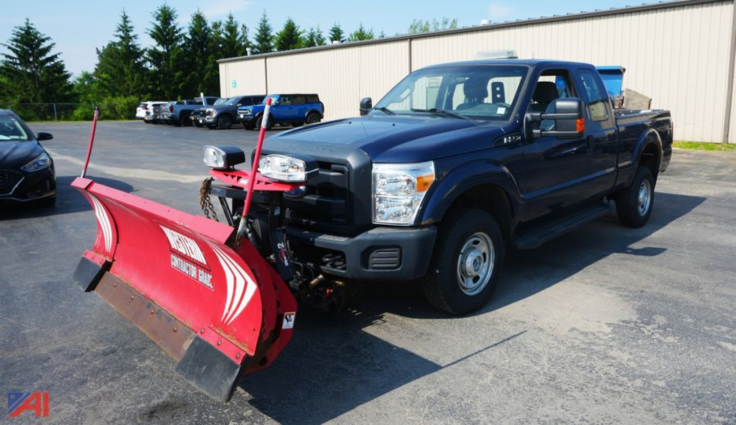Ford F-250 pickup with front snow plow attached, extended cab, dark blue, in a parking lot.
