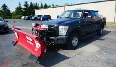 Ford F-250 pickup with front snow plow attached, extended cab, dark blue, in a parking lot.