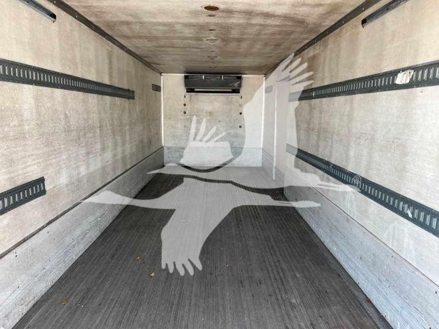 Truck interior showing empty refrigerated cargo area with white walls and black rubber floor, side rails and rear doors visible.