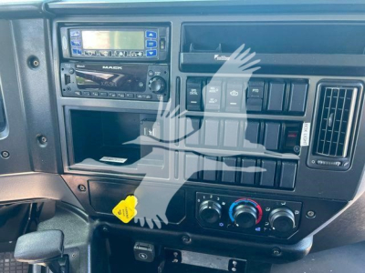 Dashboard view of 2023 Mack MD6 refrigerated truck showing radio, vents, controls, and yellow key tag.