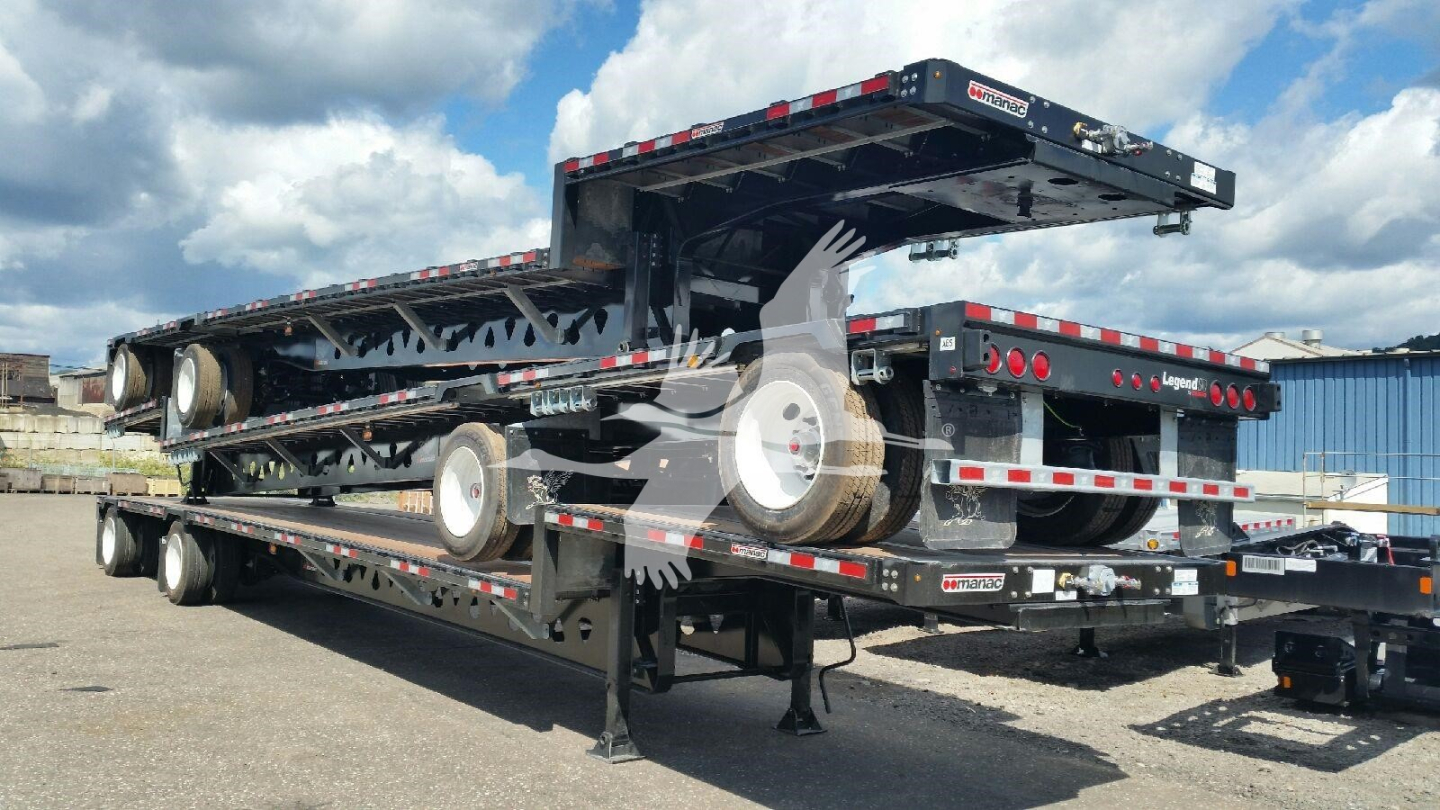 Manac dropdeck trailer in raised position showing dual level frame and wooden deck with wheels and support stands.