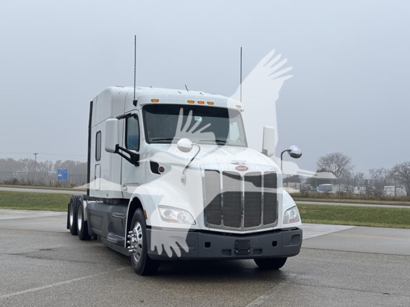 Peterbilt 579 conventional sleeper truck in a parking lot, front three-quarter view.
