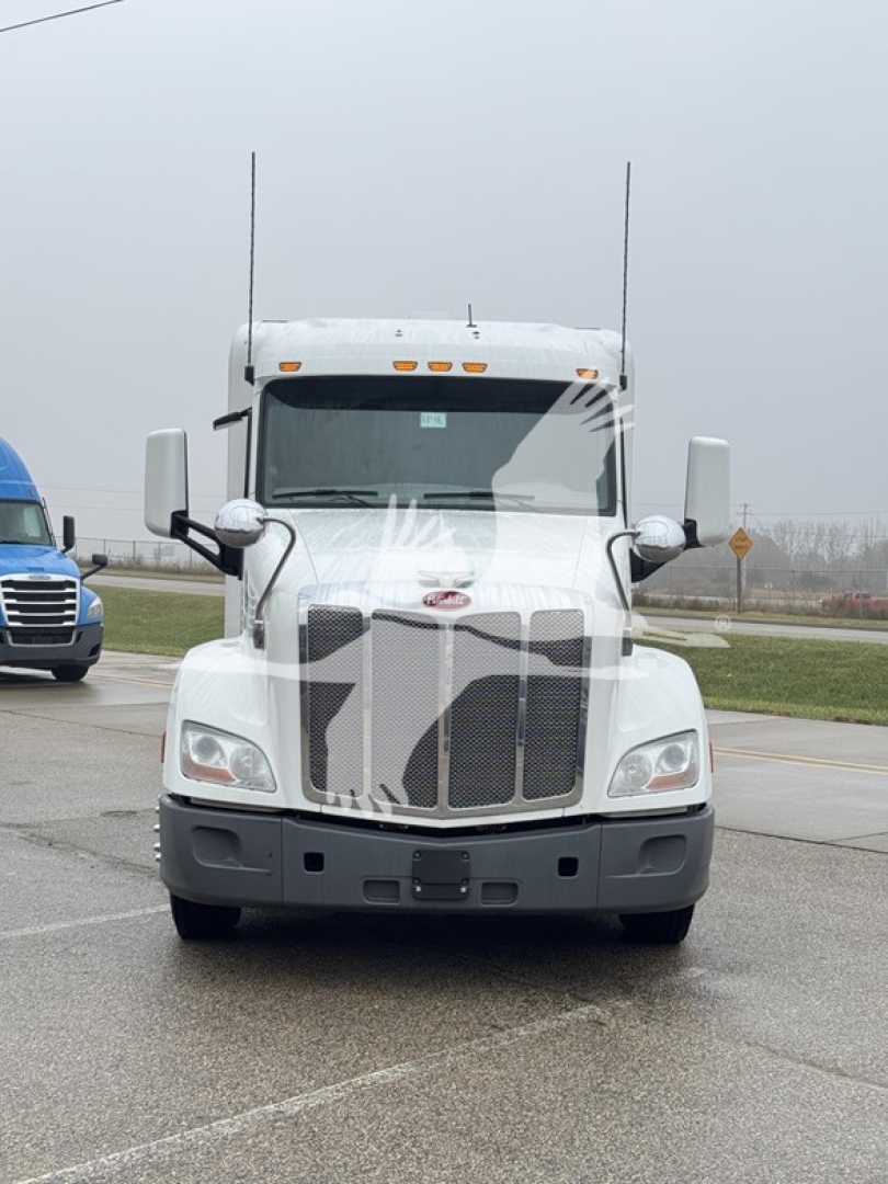 Peterbilt 579 conventional sleeper truck front view with chrome grille and dual antennas.