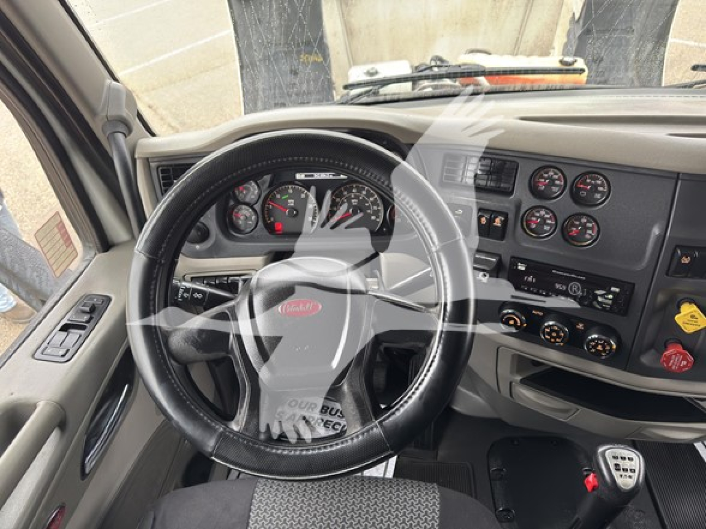 Peterbilt truck interior showing steering wheel and dashboard with multiple gauges.